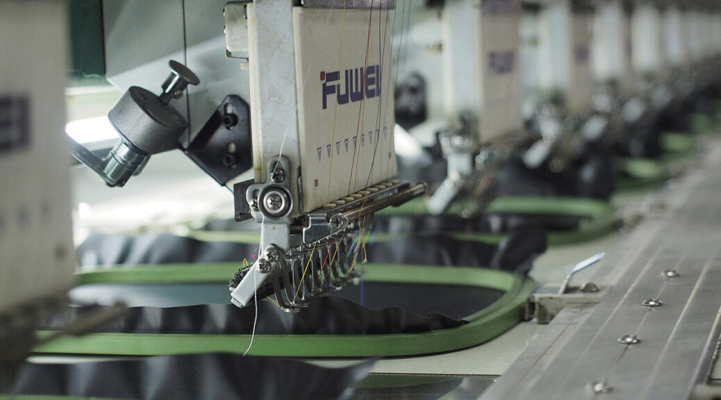 Close-up of automated embroidery machines stitching fabric in a production line.